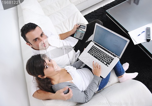 Image of joyful couple relax and work on laptop computer at modern home