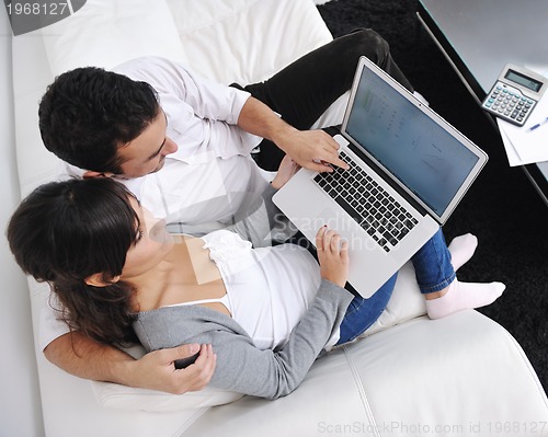 Image of joyful couple relax and work on laptop computer at modern home