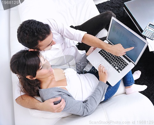 Image of joyful couple relax and work on laptop computer at modern home