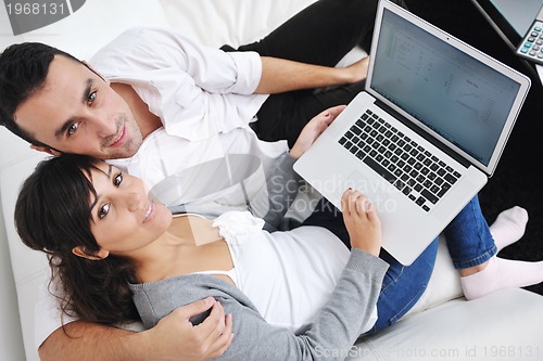 Image of joyful couple relax and work on laptop computer at modern home