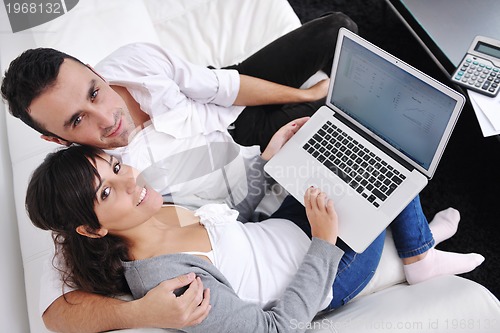 Image of joyful couple relax and work on laptop computer at modern home