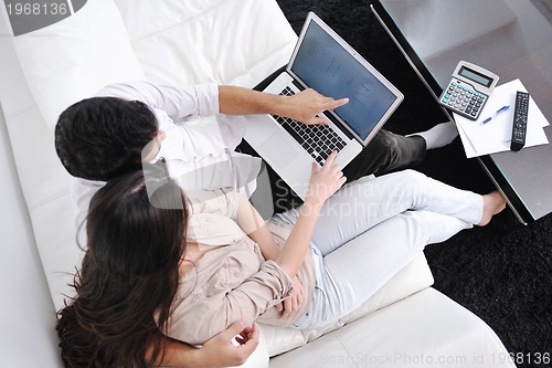 Image of joyful couple relax and work on laptop computer at modern home