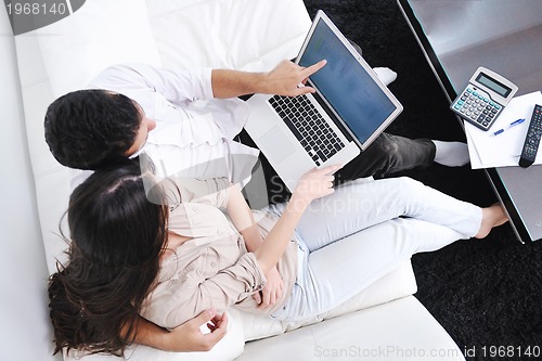 Image of joyful couple relax and work on laptop computer at modern home