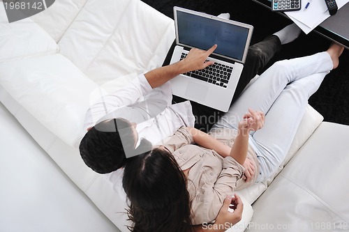 Image of joyful couple relax and work on laptop computer at modern home