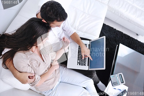 Image of joyful couple relax and work on laptop computer at modern home