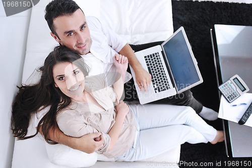 Image of joyful couple relax and work on laptop computer at modern home