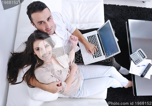 Image of joyful couple relax and work on laptop computer at modern home