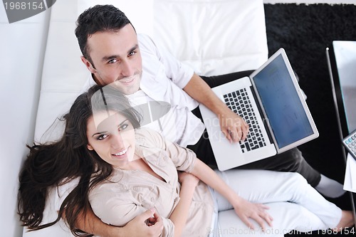 Image of joyful couple relax and work on laptop computer at modern home