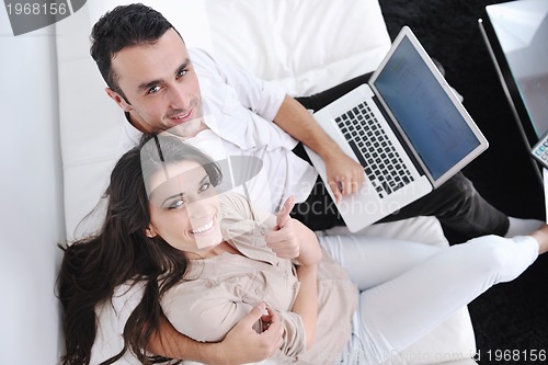 Image of joyful couple relax and work on laptop computer at modern home