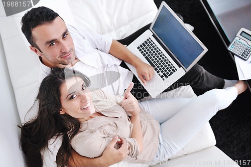 Image of joyful couple relax and work on laptop computer at modern home