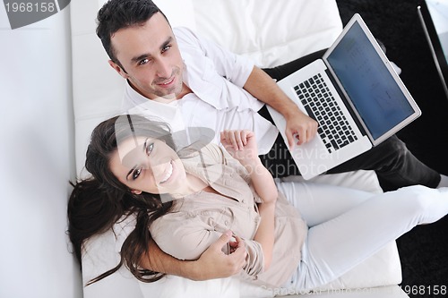 Image of joyful couple relax and work on laptop computer at modern home