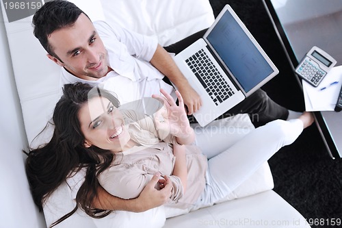 Image of joyful couple relax and work on laptop computer at modern home