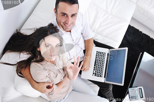 Image of joyful couple relax and work on laptop computer at modern home