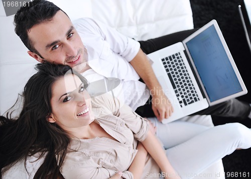 Image of joyful couple relax and work on laptop computer at modern home