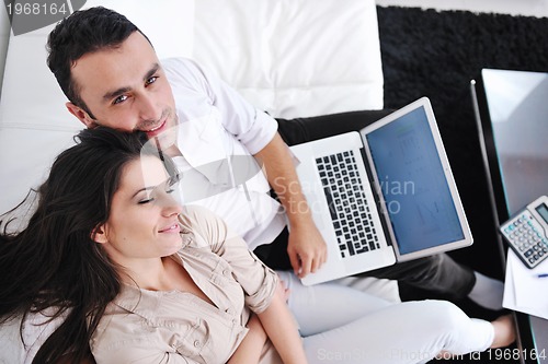 Image of joyful couple relax and work on laptop computer at modern home