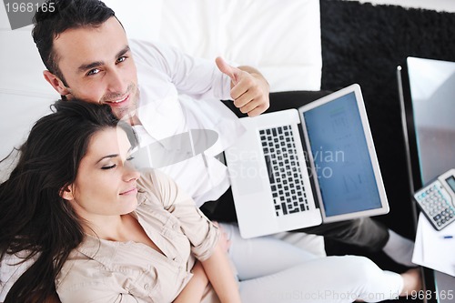 Image of joyful couple relax and work on laptop computer at modern home