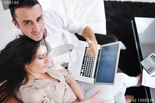 Image of joyful couple relax and work on laptop computer at modern home