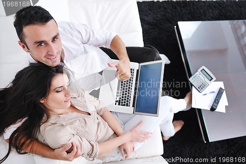 Image of joyful couple relax and work on laptop computer at modern home
