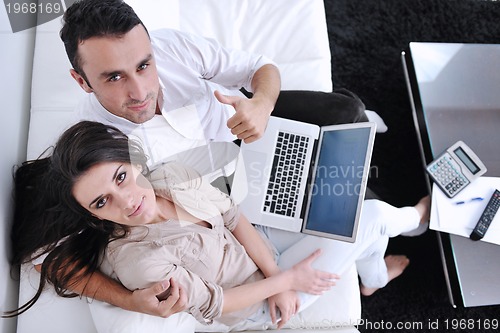 Image of joyful couple relax and work on laptop computer at modern home