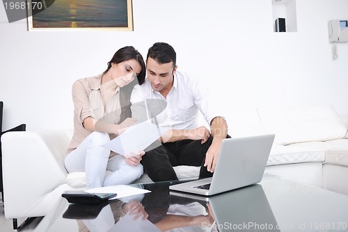 Image of joyful couple relax and work on laptop computer at modern home
