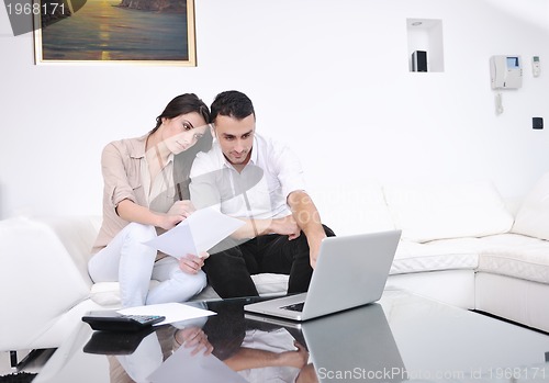 Image of joyful couple relax and work on laptop computer at modern home