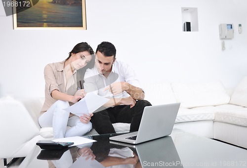 Image of joyful couple relax and work on laptop computer at modern home