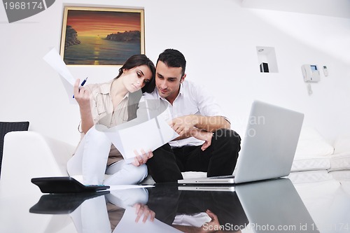 Image of joyful couple relax and work on laptop computer at modern home