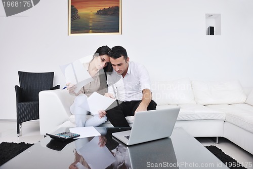 Image of joyful couple relax and work on laptop computer at modern home