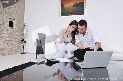 Image of joyful couple relax and work on laptop computer at modern home