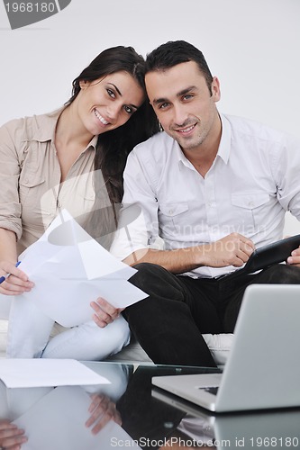 Image of joyful couple relax and work on laptop computer at modern home