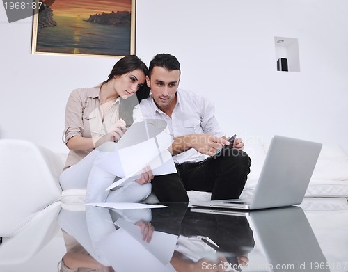 Image of joyful couple relax and work on laptop computer at modern home