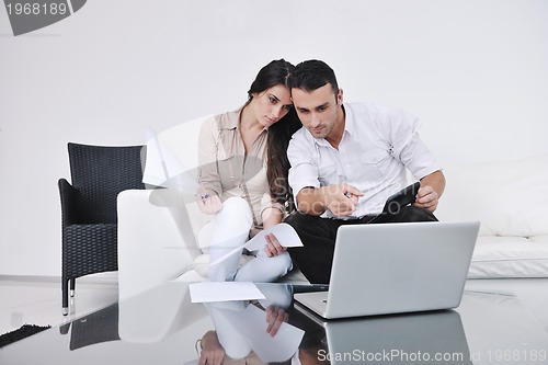 Image of joyful couple relax and work on laptop computer at modern home