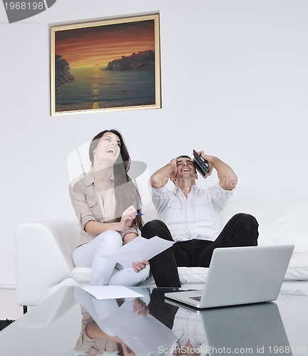 Image of joyful couple relax and work on laptop computer at modern home