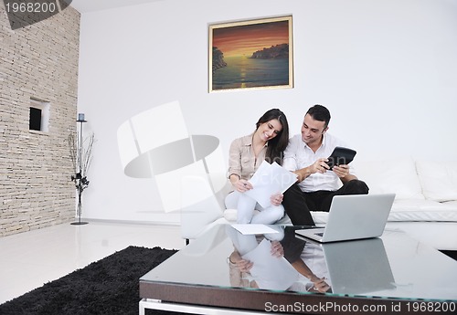 Image of joyful couple relax and work on laptop computer at modern home