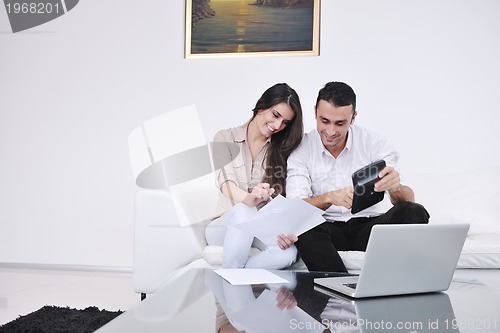 Image of joyful couple relax and work on laptop computer at modern home
