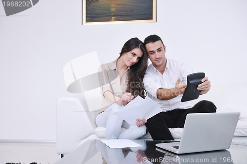 Image of joyful couple relax and work on laptop computer at modern home