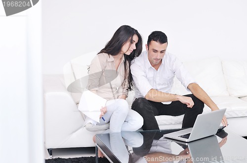 Image of joyful couple relax and work on laptop computer at modern home