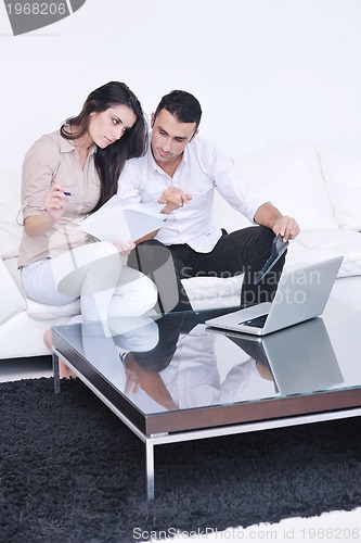 Image of joyful couple relax and work on laptop computer at modern home