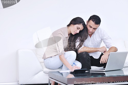 Image of joyful couple relax and work on laptop computer at modern home