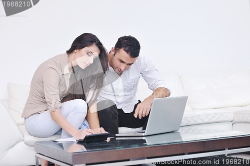 Image of joyful couple relax and work on laptop computer at modern home