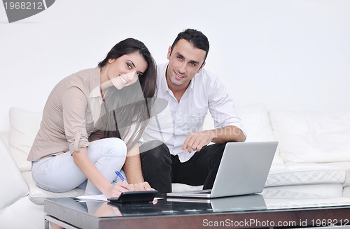 Image of joyful couple relax and work on laptop computer at modern home