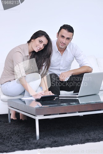 Image of joyful couple relax and work on laptop computer at modern home