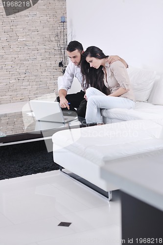 Image of joyful couple relax and work on laptop computer at modern home