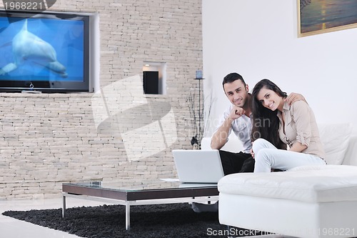Image of joyful couple relax and work on laptop computer at modern home
