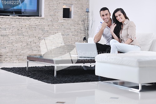 Image of joyful couple relax and work on laptop computer at modern home