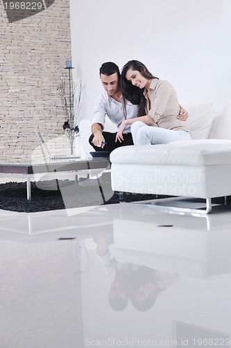 Image of joyful couple relax and work on laptop computer at modern home