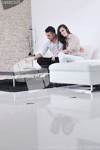 Image of joyful couple relax and work on laptop computer at modern home