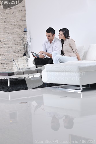 Image of joyful couple relax and work on laptop computer at modern home