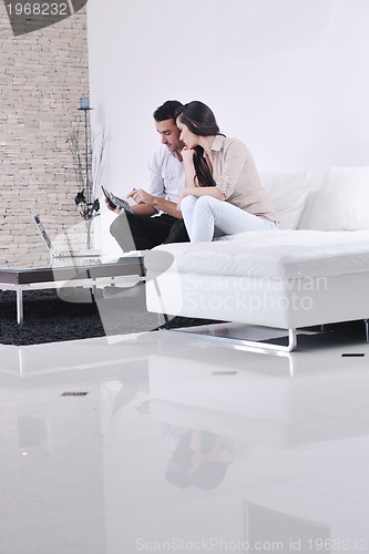 Image of joyful couple relax and work on laptop computer at modern home