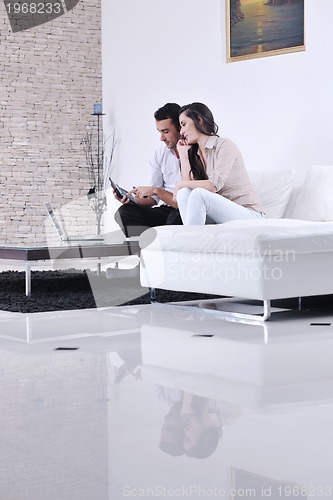 Image of joyful couple relax and work on laptop computer at modern home